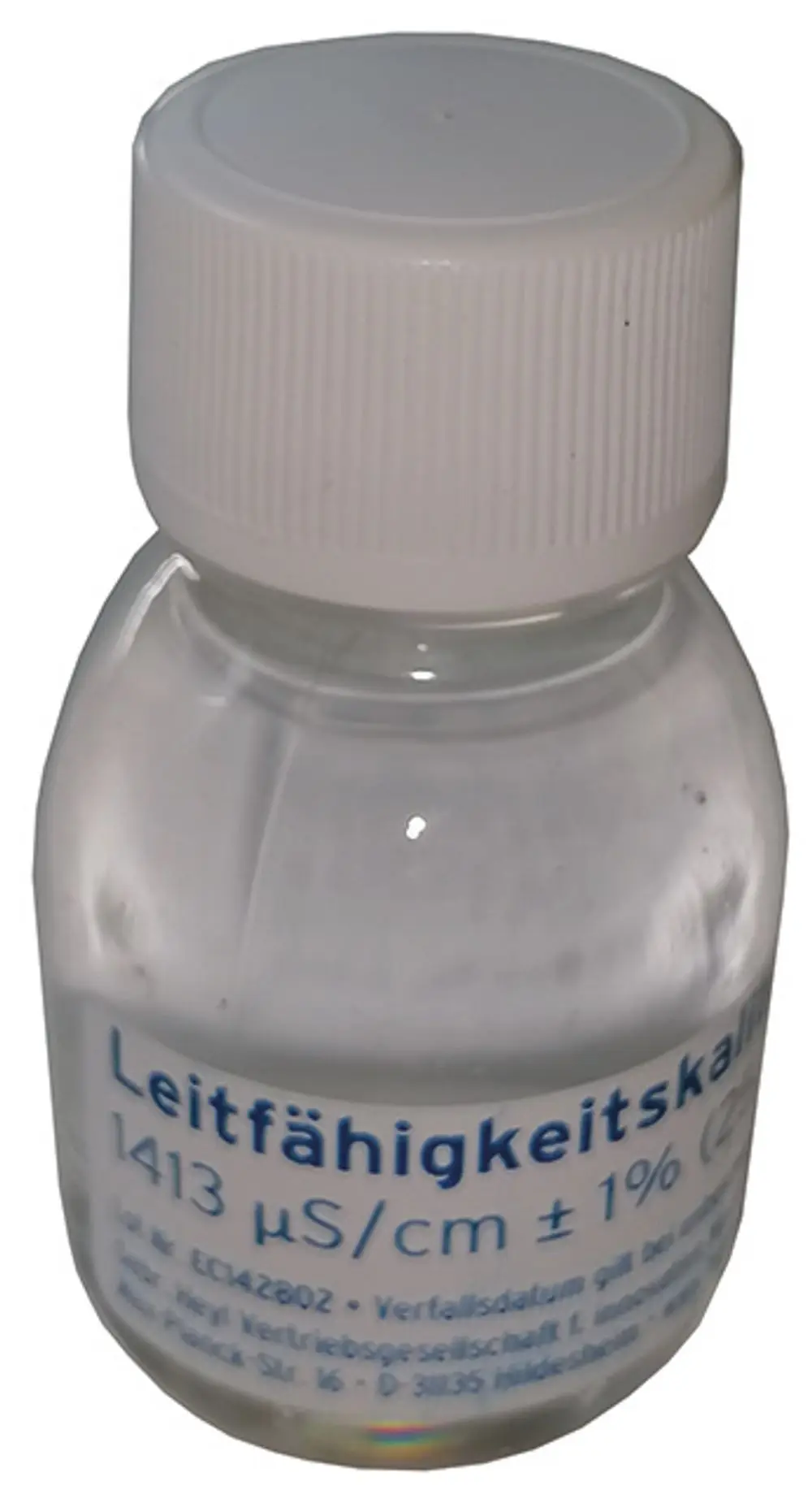 Transparente Flasche mit weißem Deckel. Aufschrift mit elektrischer Leitfähigkeit von 1413 µS/cm. Herstellerangabe: Syr.  Verfallsdatum und weitere Informationen auf dem Etikett.